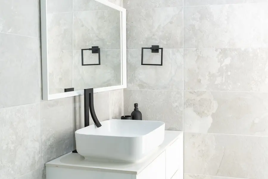 A bathroom with a square sink, mirror, and towel racks.