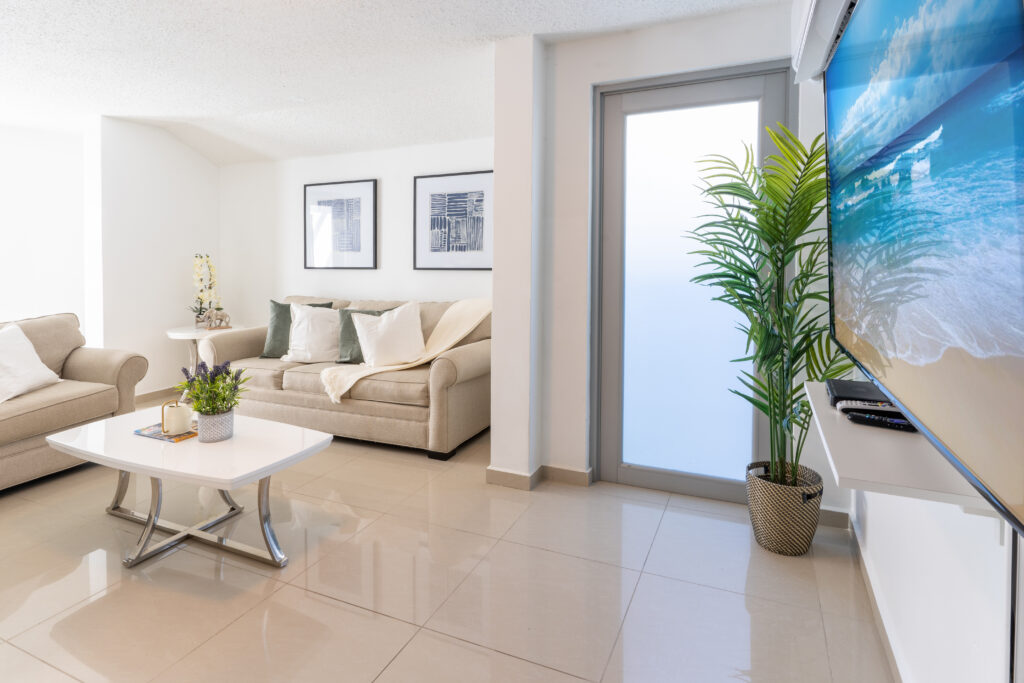 Inviting living room at AQUA Ville Moderna in Puerto Rico, featuring stylish decor, comfortable seating, and natural light pouring in through large windows, creating a welcoming ambiance.